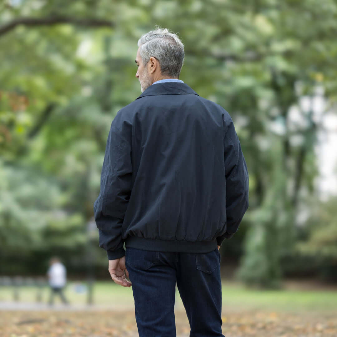 Man wearing a navy weatherproof jacket outdoors, showcasing adaptive design for comfort and mobility.