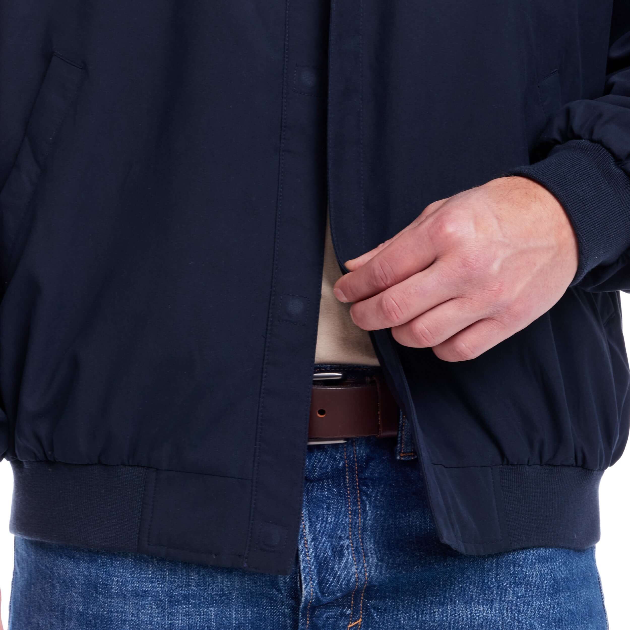 Close-up of person using magnetic closure on navy weatherproof golf jacket, designed for accessibility and style.