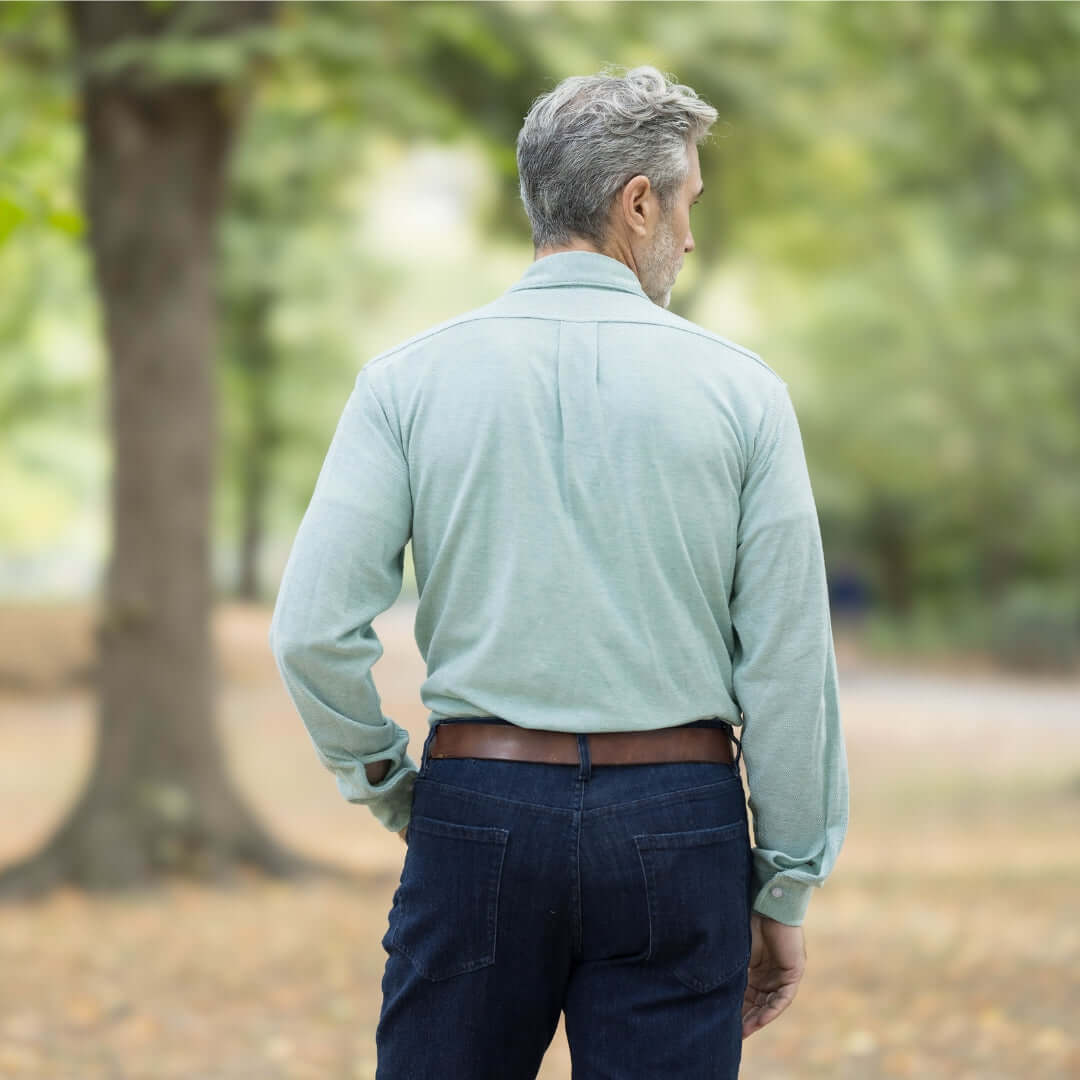 Man wearing a green long sleeve shirt in a natural setting, showcasing the back view.