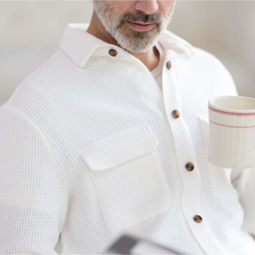 Man wearing a white waffle weave casual shirt with dual oversized pockets, holding a cup.
