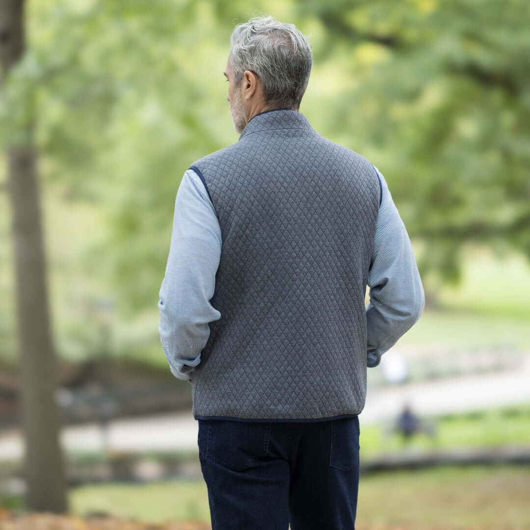 Man wearing a gray MagnaReady® Reversible Diamond Quilted Magnetic Button Vest, seen from the back in a natural setting.