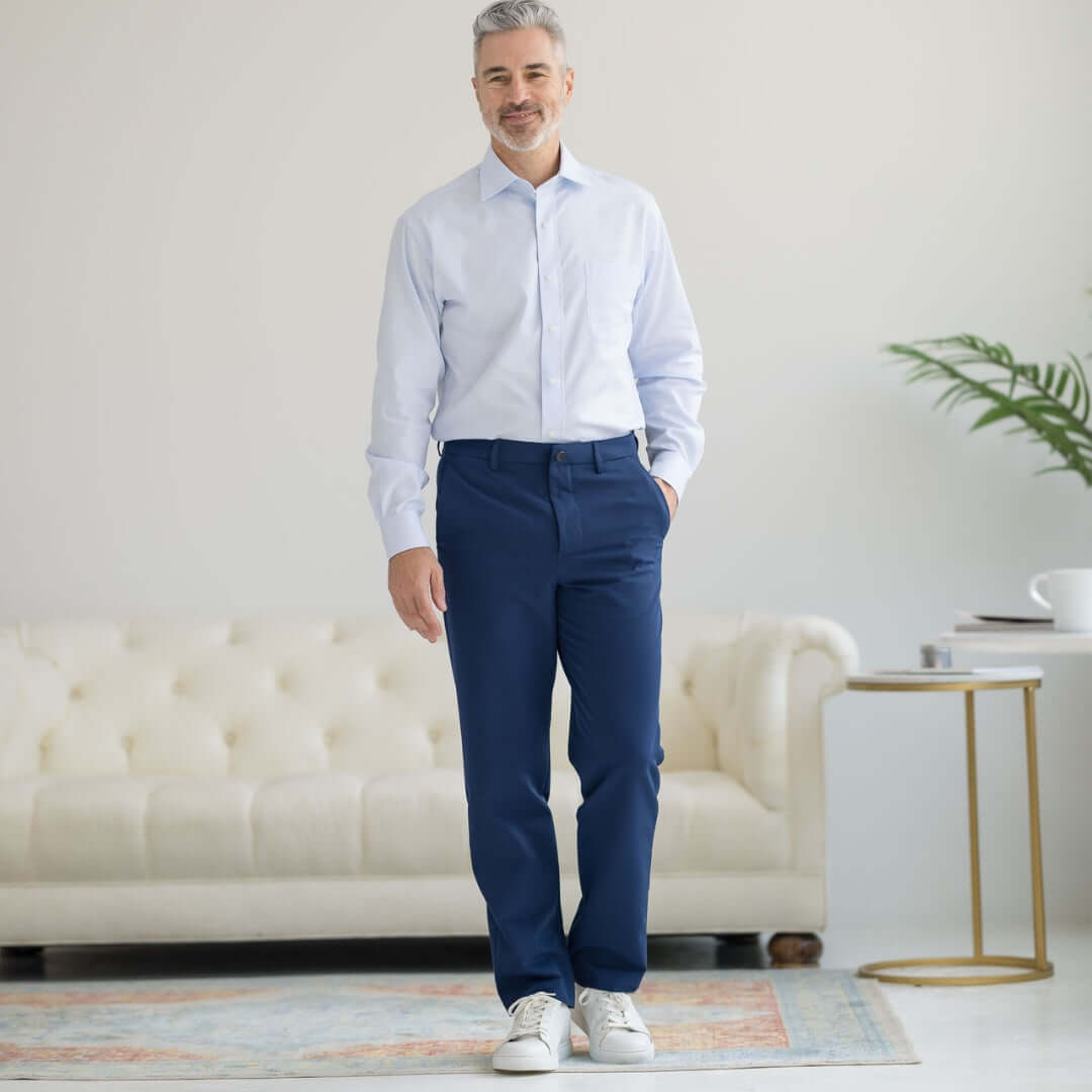 Man in navy adaptive dress pants and light blue shirt, showcasing modern comfort and style in a sophisticated setting.