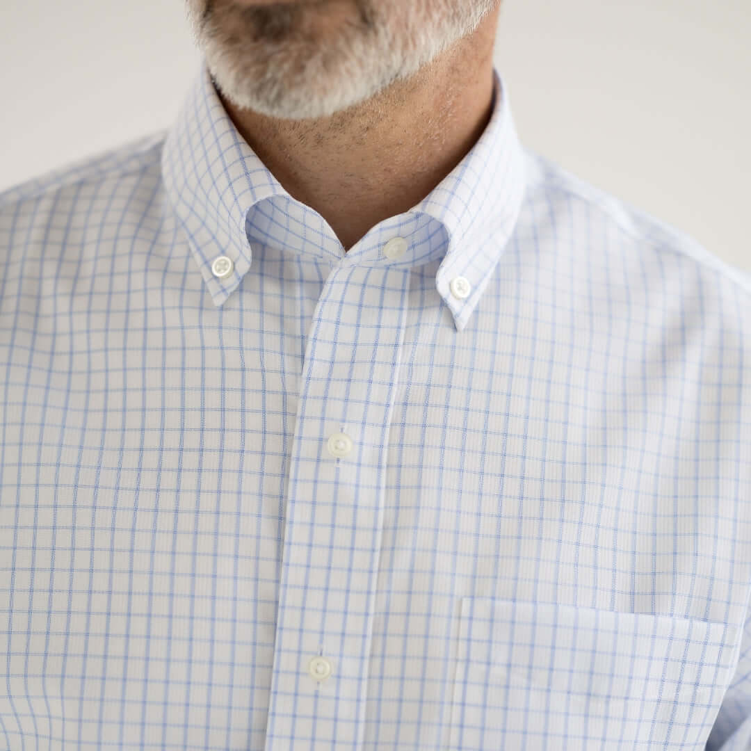 Close-up of a man wearing a navy grid long sleeve button-down collar shirt with magnetic closures.