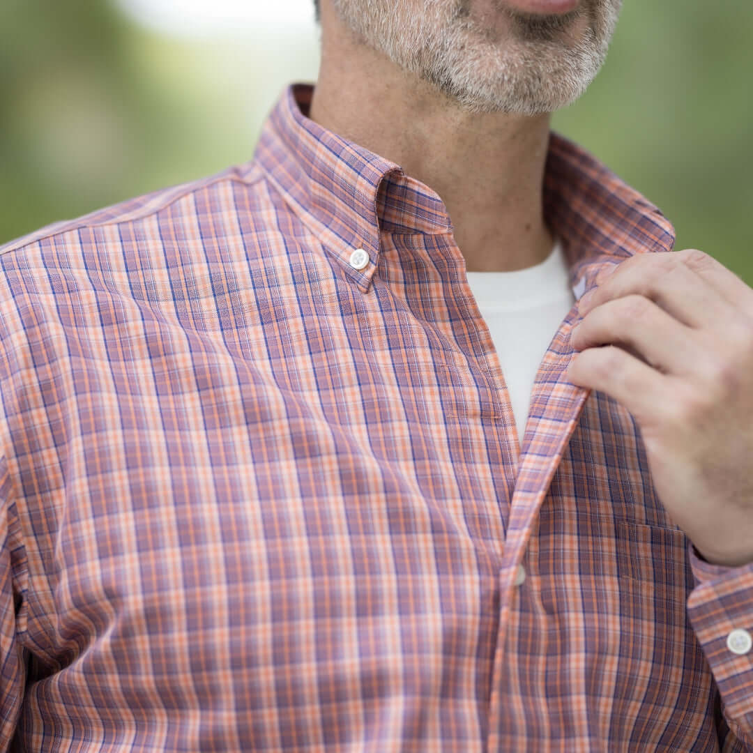 Man wearing an orange long sleeve button-down shirt with a plaid pattern and magnetic closures.