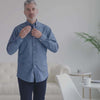 Man adjusting a blue chambray shirt with magnetic closures, showcasing adaptive fashion for easy dressing.