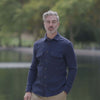 Man modeling a navy waffle knit shirt with dual pockets by a serene lake.
