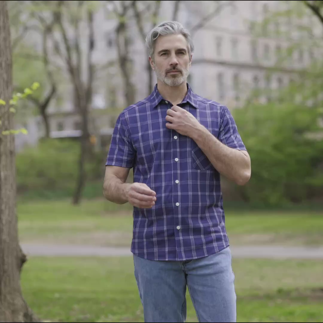 Adaptive Cooling Magnetic Front Short Sleeve Shirt in Navy Windowpane worn by a man outdoors in a park.