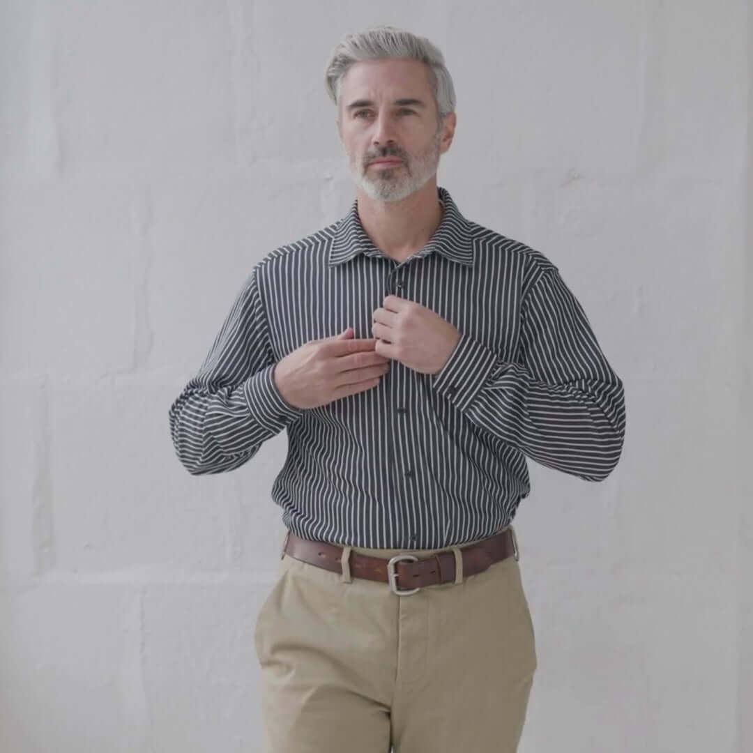 Stylish man wearing MagnaReady black stripe magnetic long sleeve shirt, demonstrating ease of wear in a subtle setting.