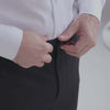 Close-up of hands adjusting the waistband of Nautica x MagnaReady adaptive stretch dress pant in black.