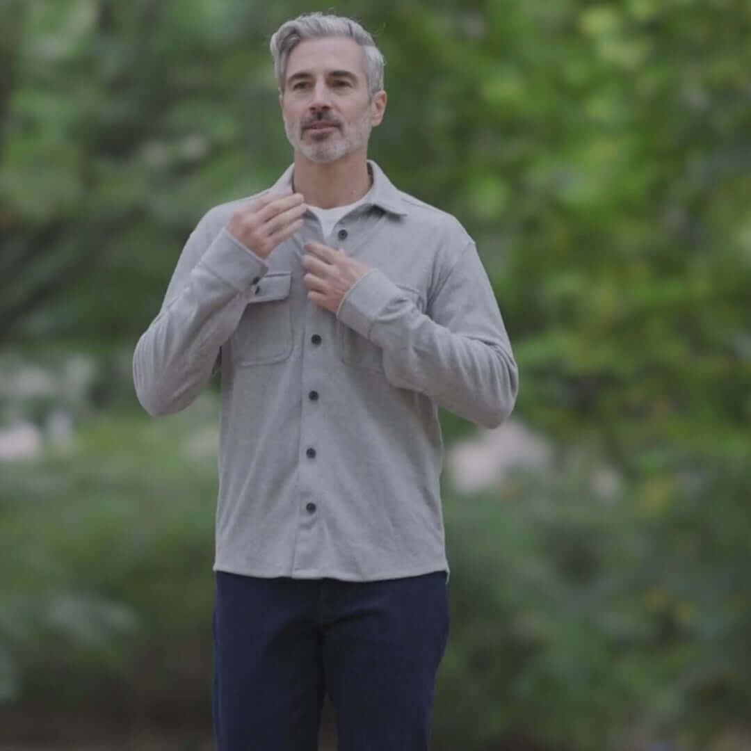 Stylish man wearing an adaptive grey flannel shirt outdoors, showcasing a versatile layering piece.