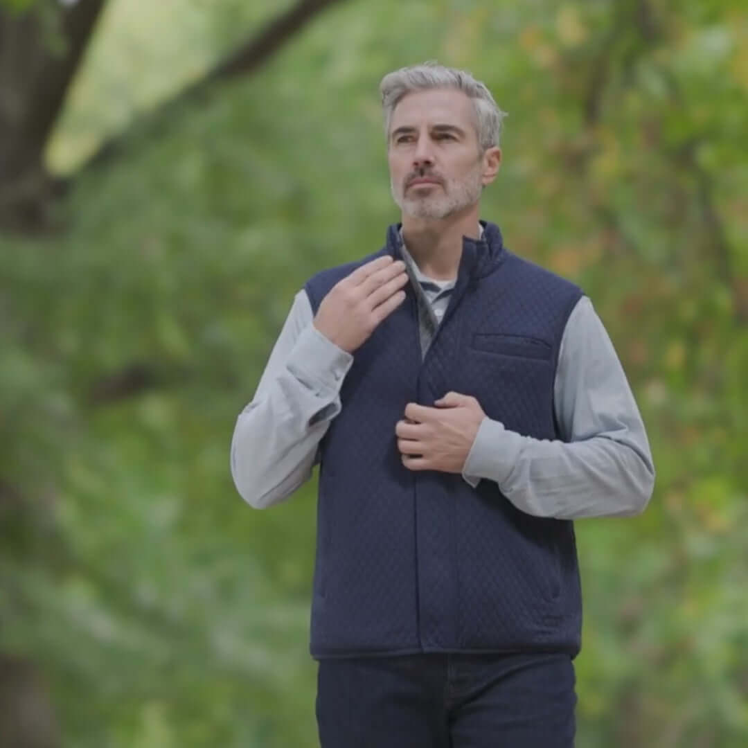 Man in navy diamond quilted magnetic vest outdoors, showcasing stylish adaptive wear for comfort and elegance.