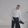 Man in white shirt preparing to wear a MagnaReady golf jacket, showcasing adaptive and stylish design.