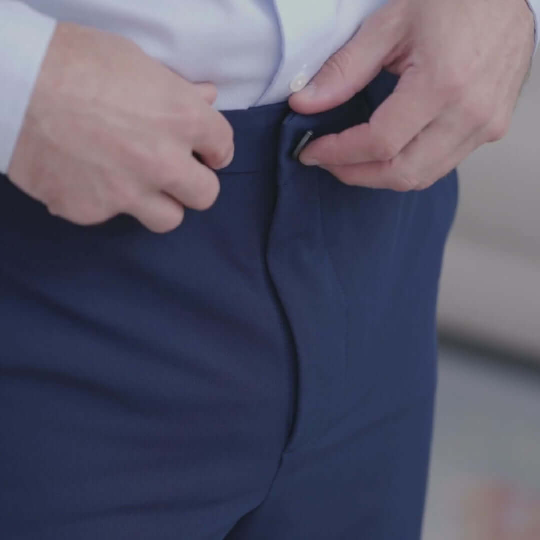 Model fastening the button of Navy Nautica® x MagnaReady® Adaptive Fly Stretch Dress Pant.