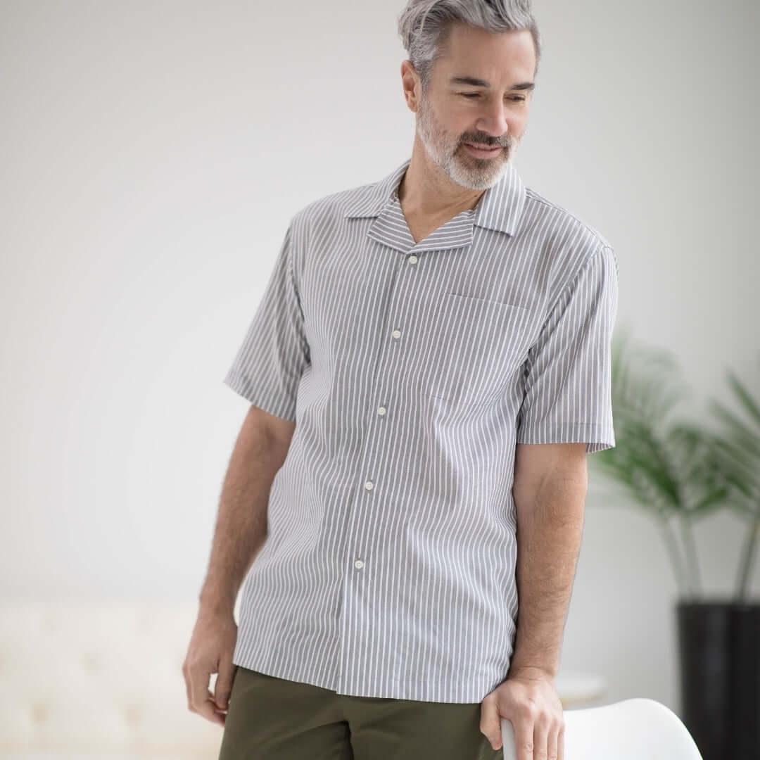 Man wearing a short sleeve untucked grey striped 'Landry' camp shirt with a modern casual style.