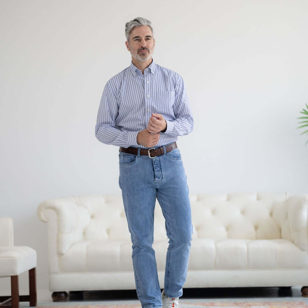 Man in a blue stripe button-down shirt with magnetic closures, standing in a stylish living room.