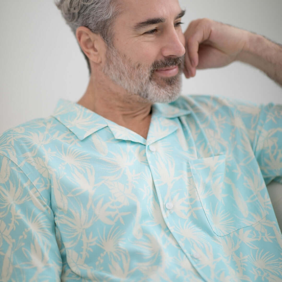 Man wearing an untucked cooling short sleeve shirt in blue leaf design, comfortable and adaptive for mobility needs.