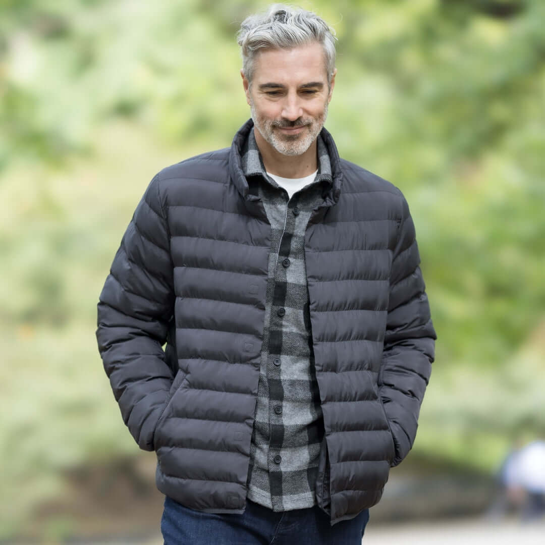 Man wearing Weatherproof x MagnaReady black puffer jacket with magnetic closure, walking outdoors.