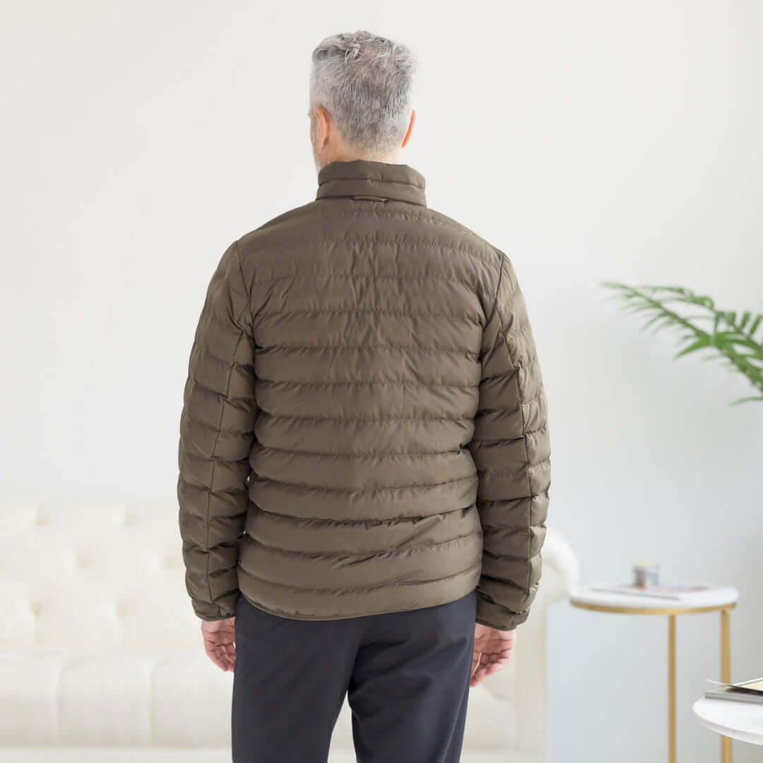 Back view of a man wearing the olive Weatherproof x MagnaReady water-resistant puffer jacket indoors.