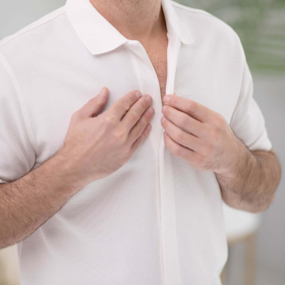 Close-up of a man wearing a white pique knit polo with magnetic closures for easy dressing.