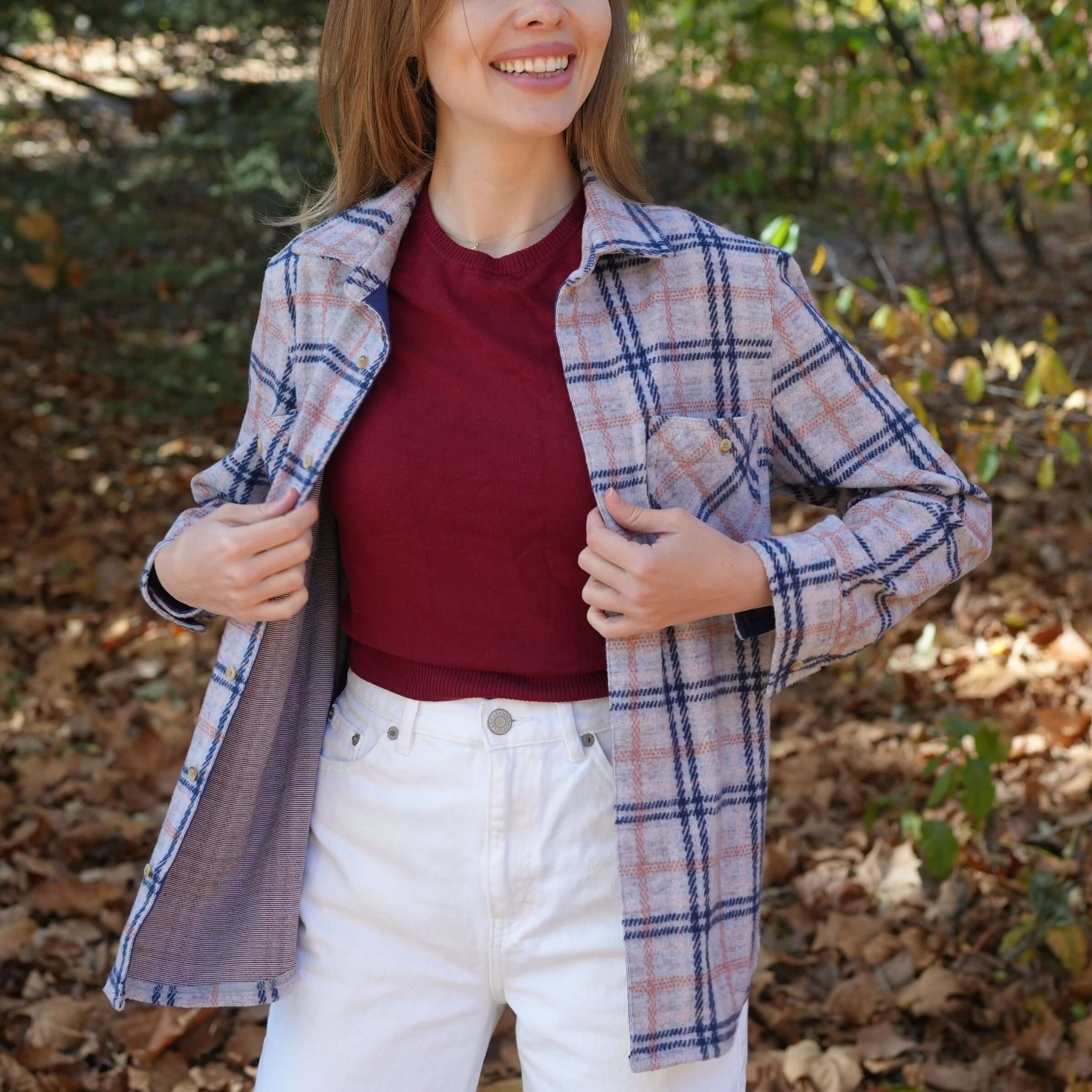 Woman wearing pink, navy, and gray flannel shirt outdoors, showcasing a stylish, adaptive design.