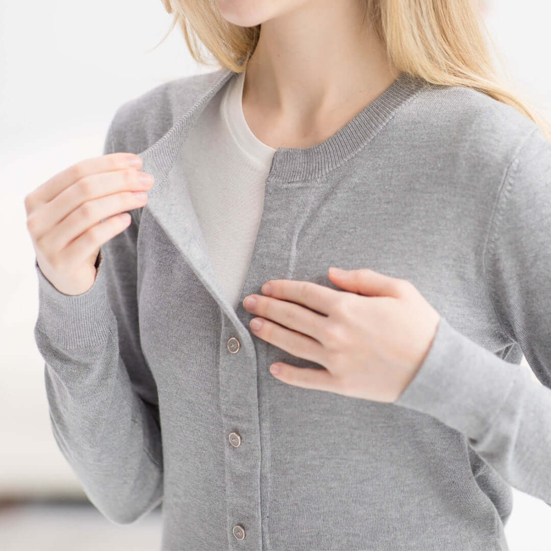 Woman in a grey adaptive magnetic front knit cardigan sweater, demonstrating easy dressing with MagnaReady® technology.