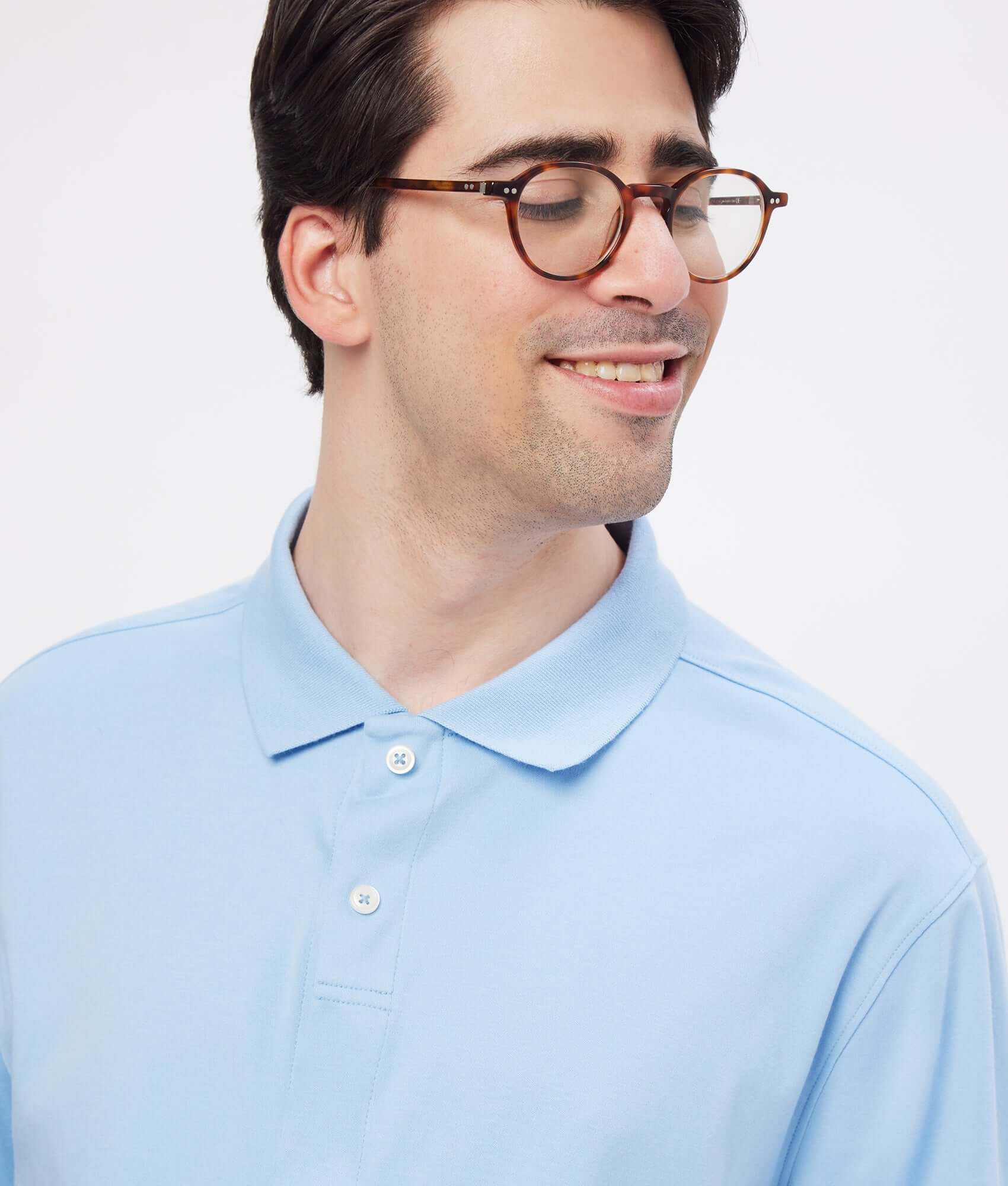 Man wearing a light blue solid interlock knit polo with a classic fit and a smile.